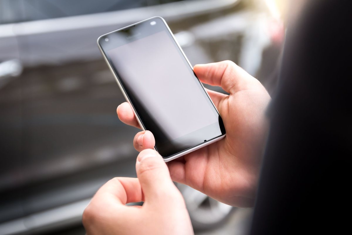 Dos manos sosteniendo un smartphone de pantalla grande en la calle