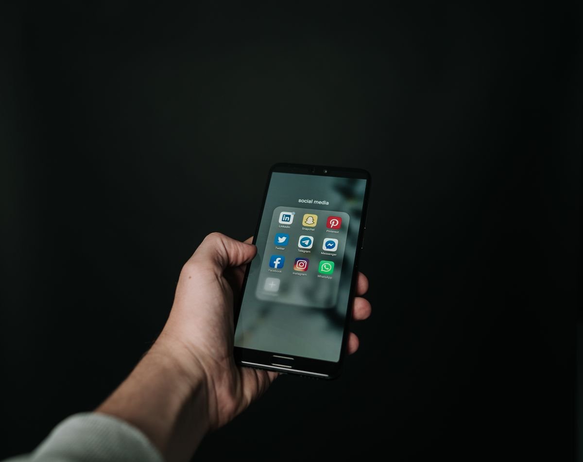 Mano sujetando un smartphone negro y manejándolo con una sola mano