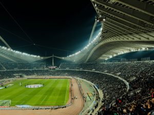 Estadio de fútbol iluminado de noche con el público en las gradas
