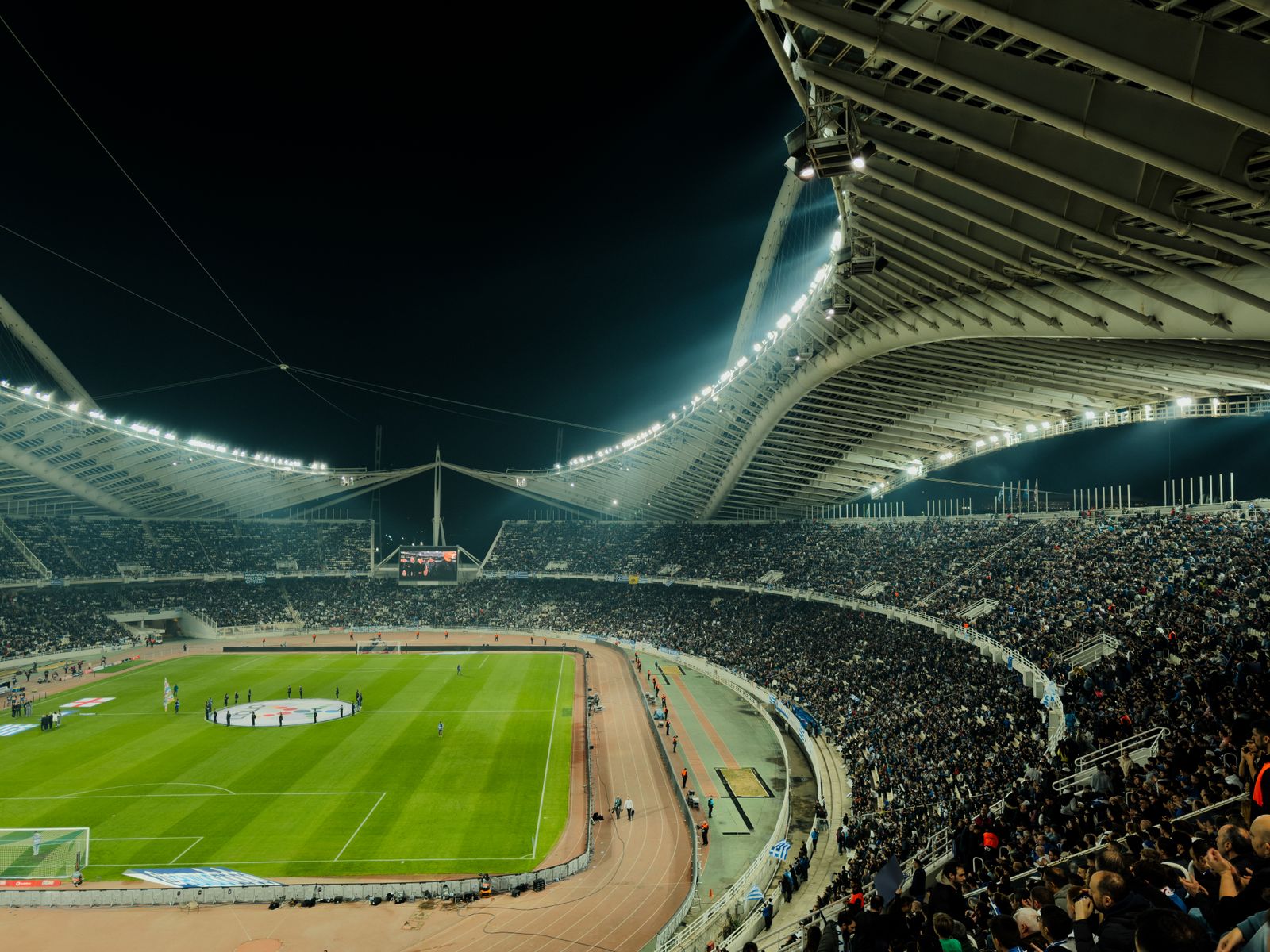 Estadio de fútbol iluminado de noche con el público en las gradas