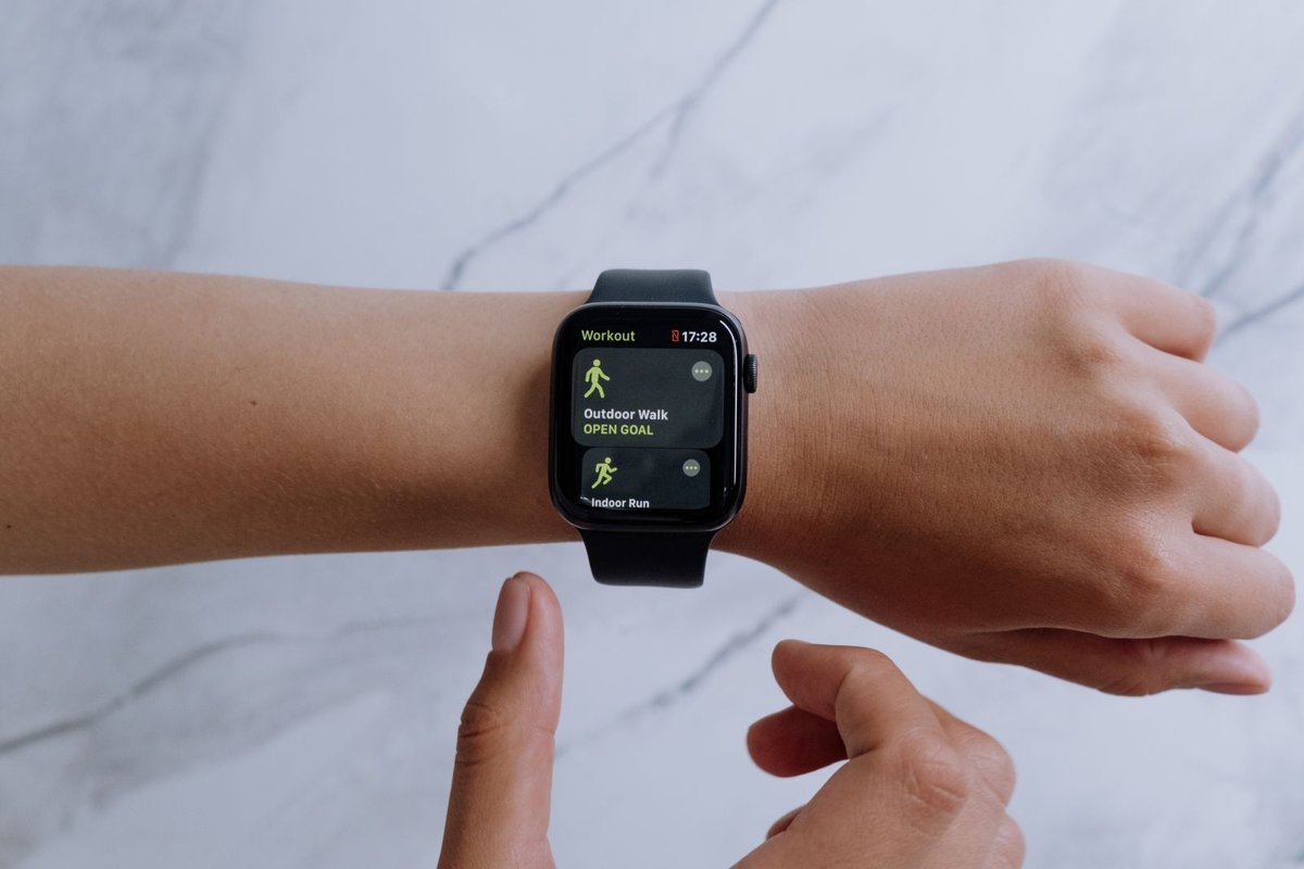 Persona usando un smartwatch negro en la muñeca con una app de entrenamiento en pantalla