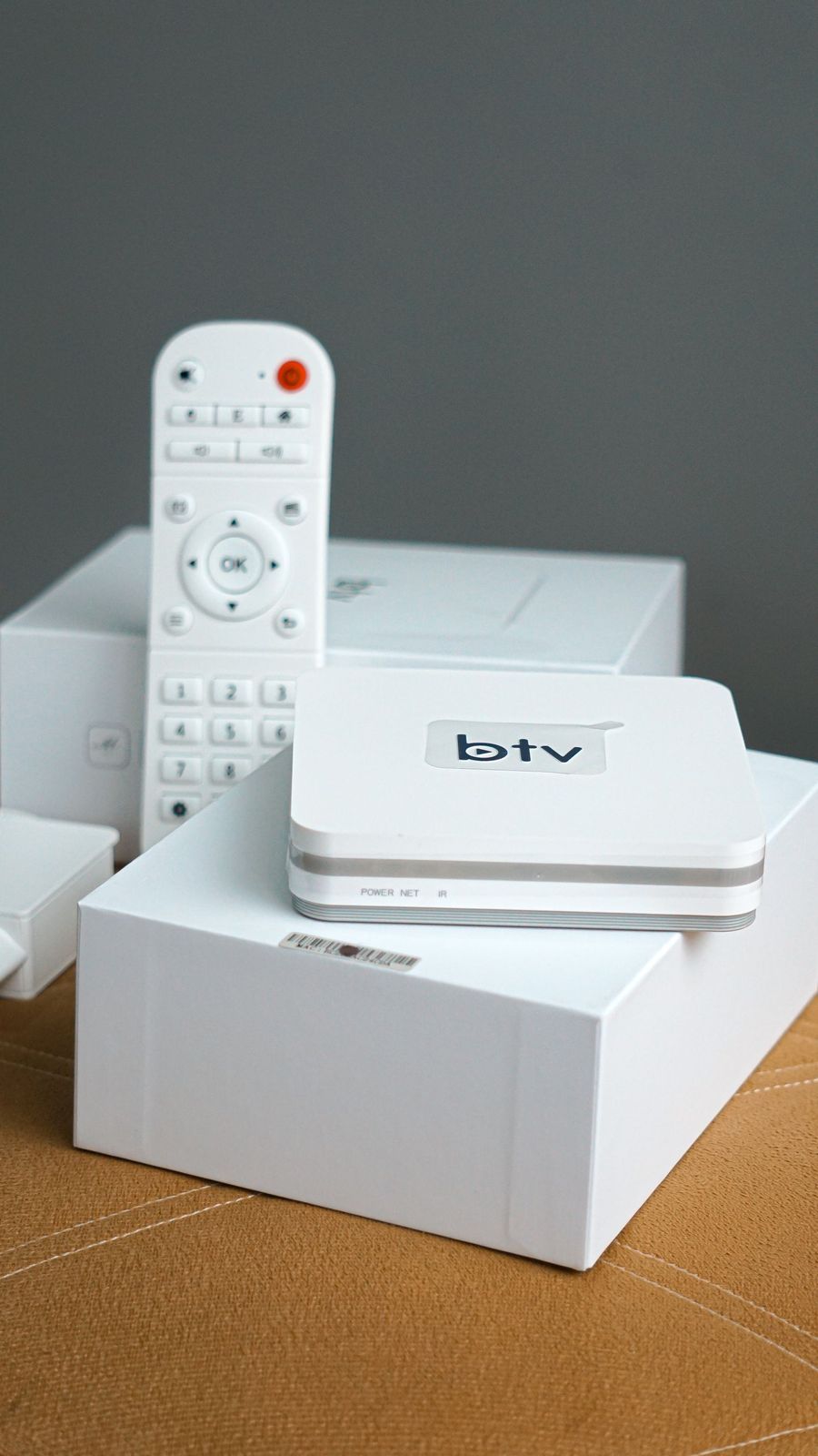 TV box Android blanco con su mando a distancia sobre la caja